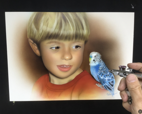 Junge mit blonden Haaren schaut fasziniert auf einen hellblauen Wellensittich.