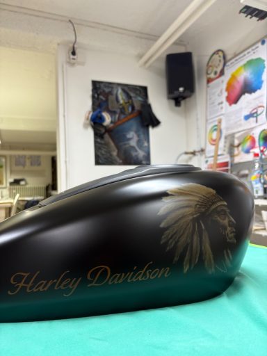 Schwarzer Motorradtank mit Indianer-Motiv und "Harley Davidson"-Schriftzug.